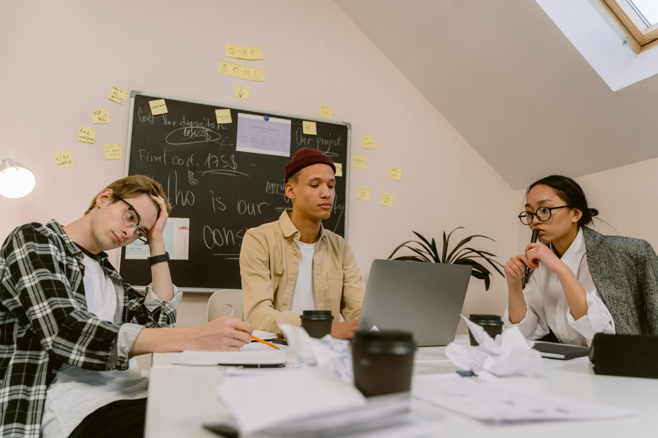 Young diverse coworkers brainstorming ideas in an office with a chalkboard.