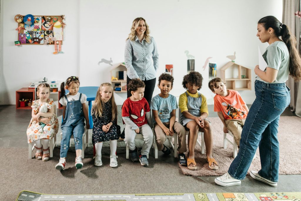 Group of children in a kindergarten classroom attending an interactive learning session with teachers.