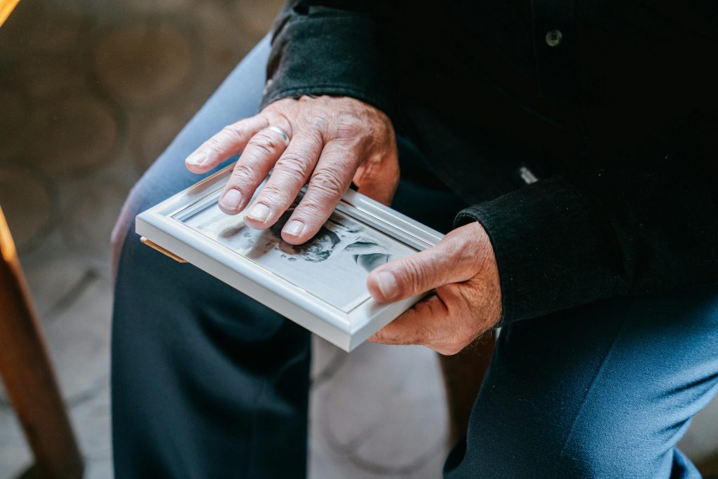 Close-up of elderly hands holding a framed photograph, reflecting nostalgia and emotion.